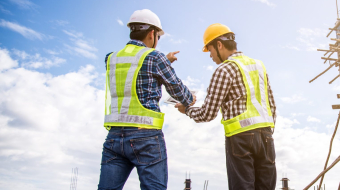 Male engineer talking with worker at a construction site with a tablet computer
