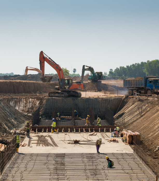 A close shot of heavy machines and construction workers working on a building